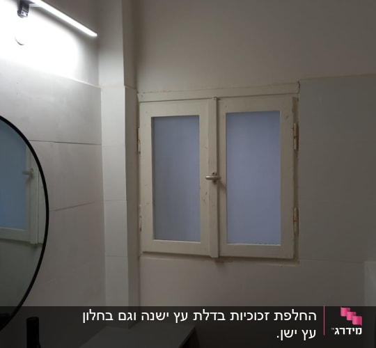 מראה עגולה וחלון זכוכית בחדר אמבטיה